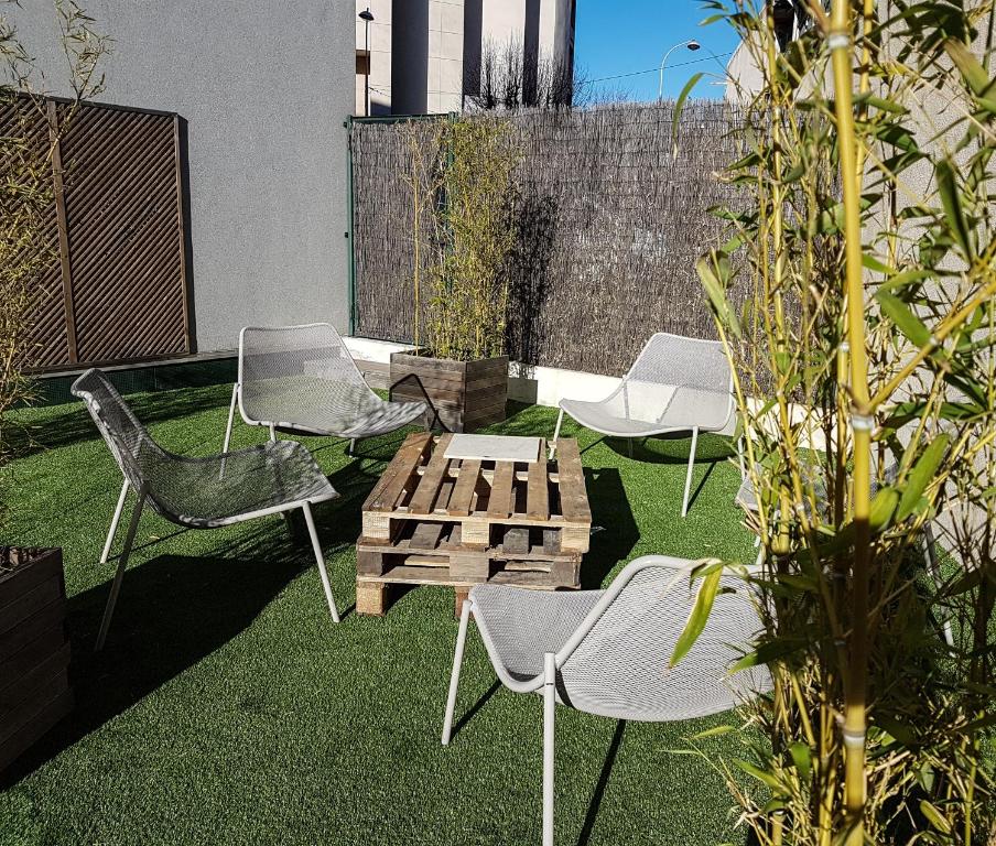 eine Terrasse mit Stühlen und einem Holztisch auf Gras in der Unterkunft Esatitude Hotel in Nizza
