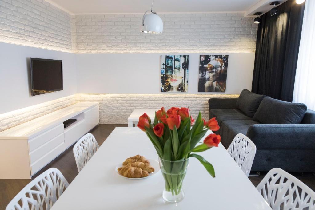 ein Wohnzimmer mit einem weißen Tisch mit Blumen in einer Vase in der Unterkunft Apartament Moniuszki by Your Freedom in Warschau