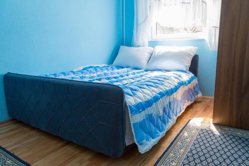 Cama en habitación azul con ventana en Apartmani Apolon, en Trebinje