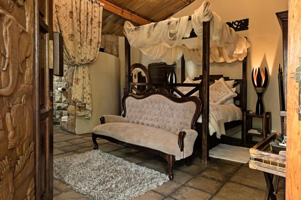 a bedroom with a canopy bed and a chair at De Loft Guesthouse in Piet Retief