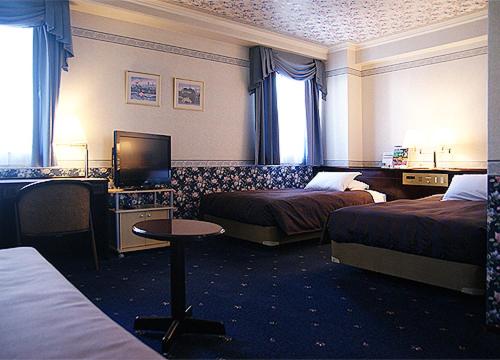 a hotel room with two beds and a television at Kurume Station Hotel in Kurume