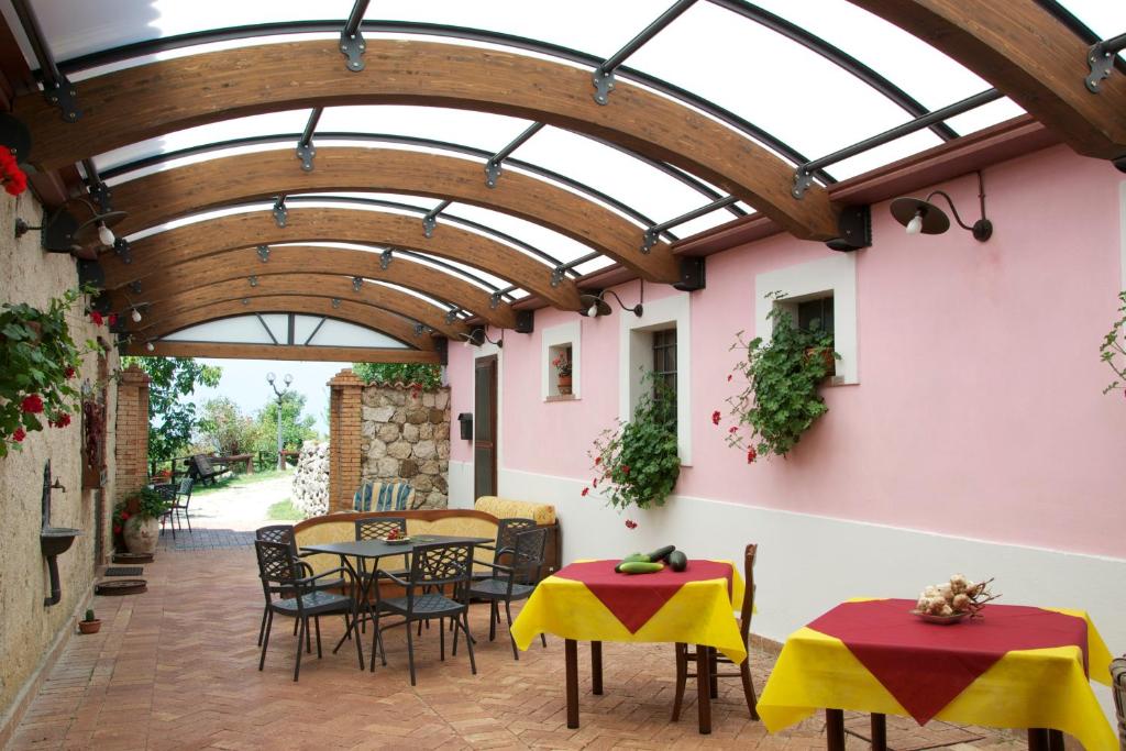 a patio with tables and chairs under a wooden ceiling at Fattoria Alvaneta in Padula