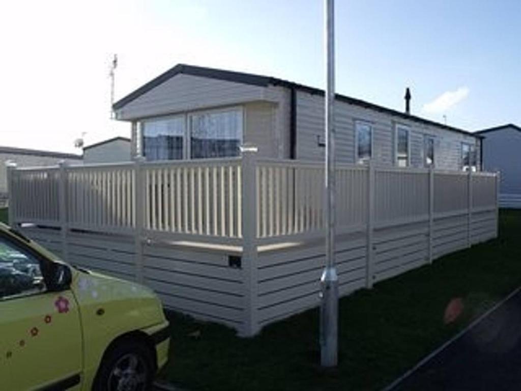 a white house with a fence next to a car at Kent Getaways in Westgate-on-Sea