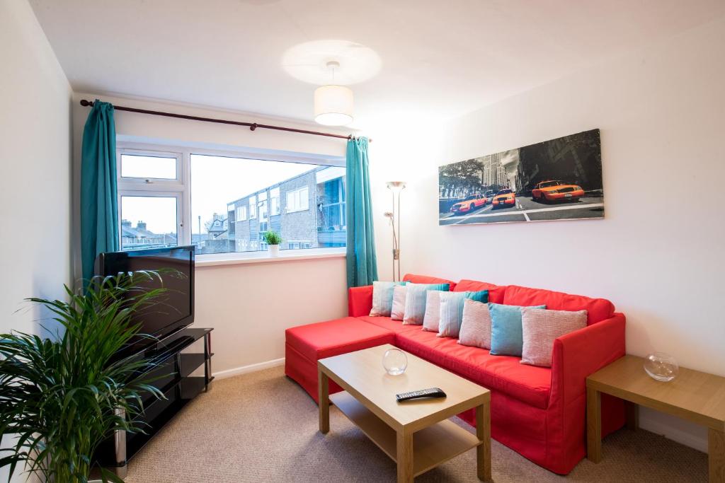 a living room with a red couch and a window at Comfy 2BR Flat with Wi-Fi in Bishop's Stortford in Bishops Stortford