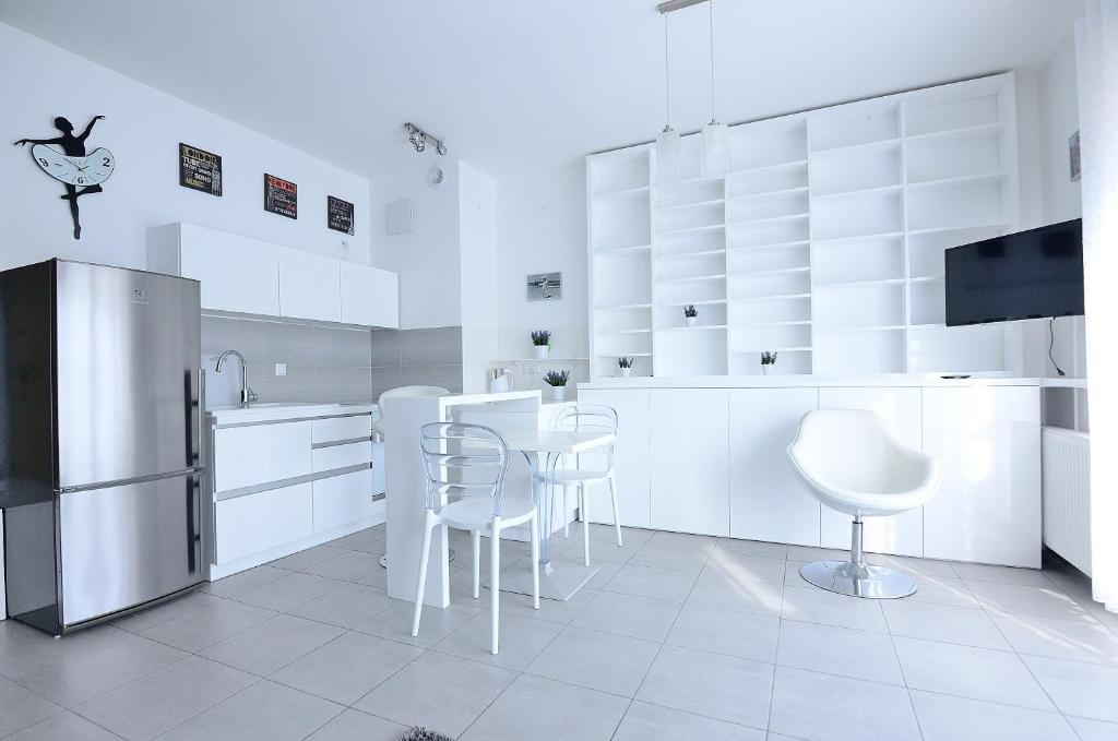 ソポトにあるVictus Apartamenty, Apartament Cadena 3の白いキッチン(白い家電製品、白い椅子付)