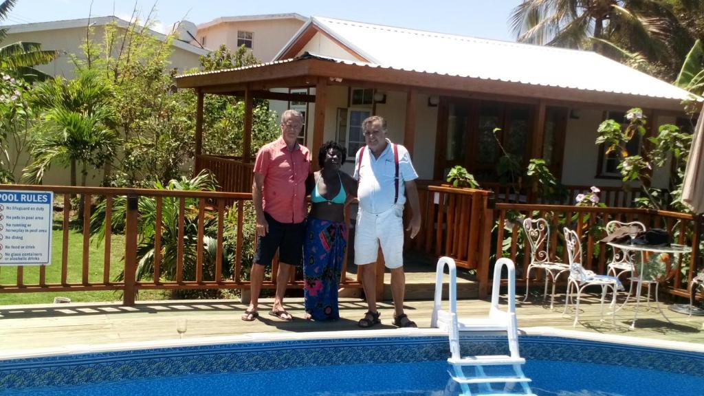 a family standing in front of a house with a pool at The Pool House in Saint Philip