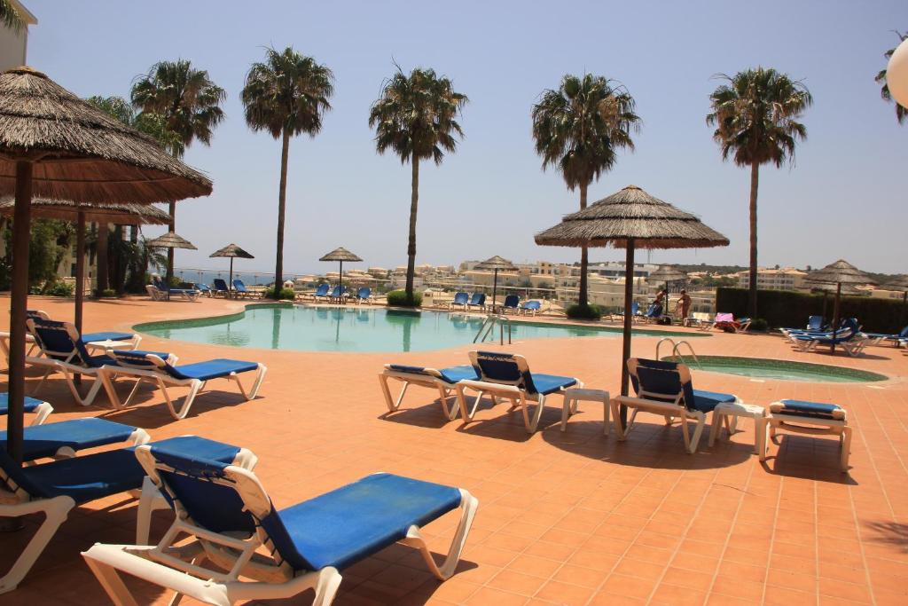 a swimming pool with lounge chairs and palm trees at Apartment Vila Mós in Porto Mós Beach in Lagos
