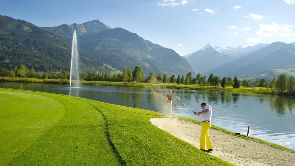 two men are standing on the shore of a lake at Hotel Garni Landhaus Gitti in Zell am See