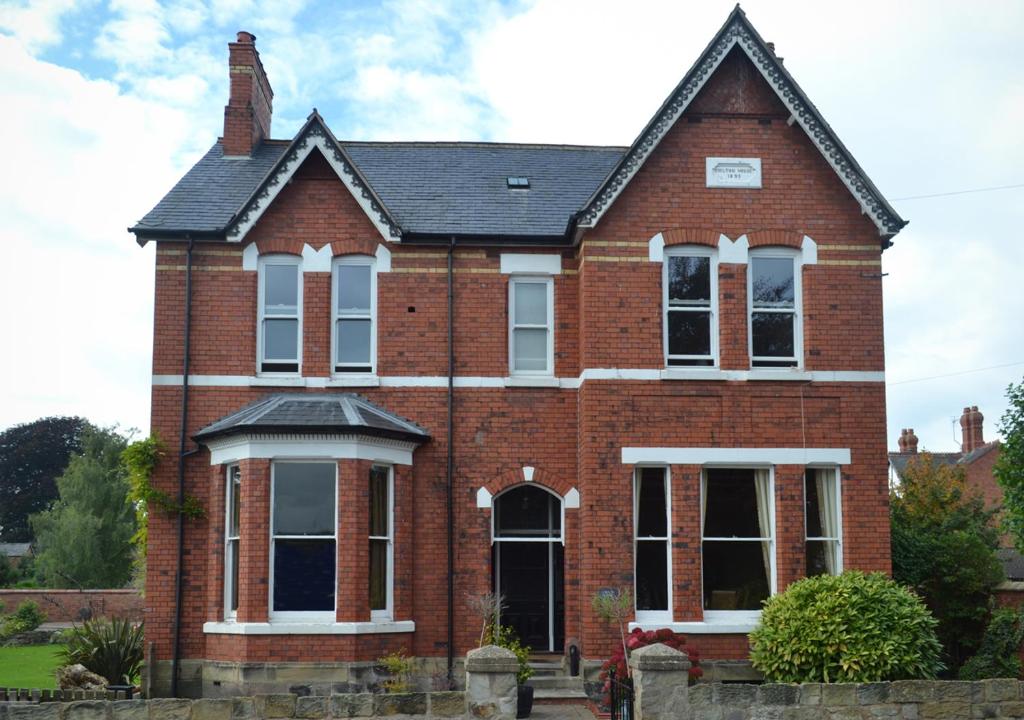 ein rotes Backsteinhaus mit schwarzem Dach in der Unterkunft Chilton House in Oswestry