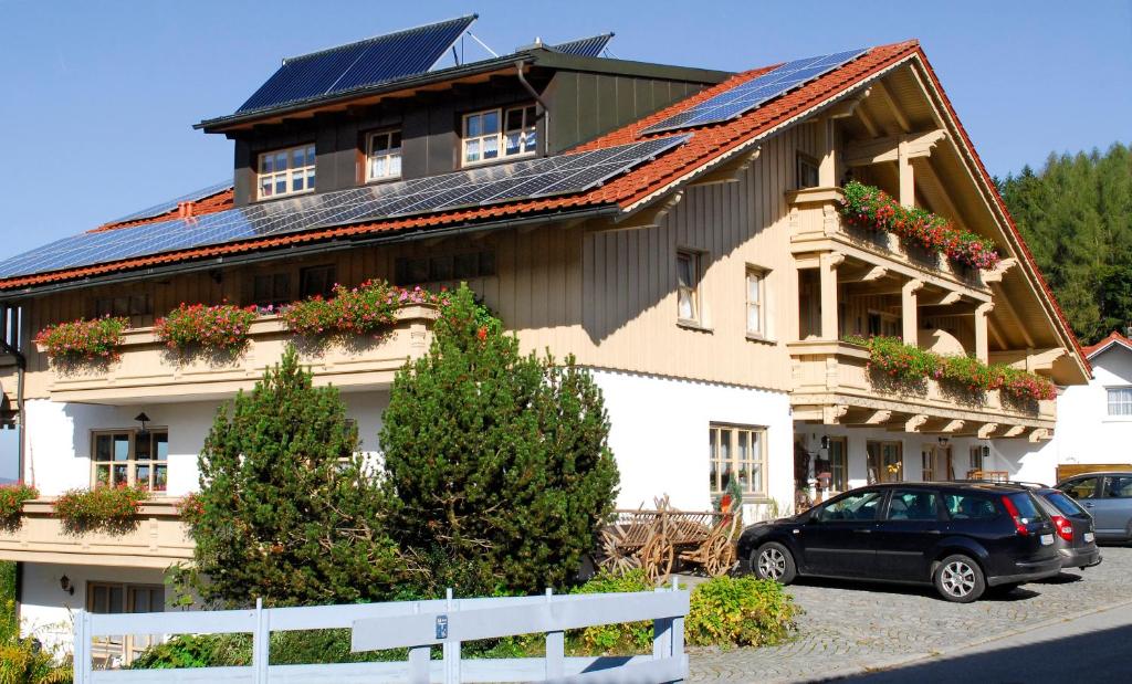 une maison avec un toit solaire et une voiture garée devant dans l'établissement Haus Vierjahreszeiten, à Bodenmais