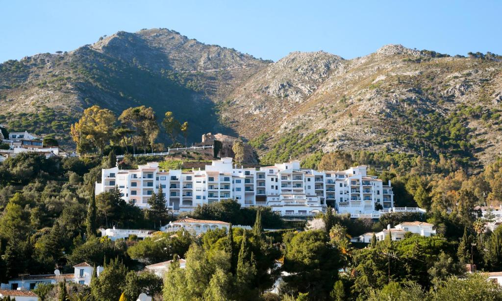 a large white apartment building on a mountain at Macdonald La Ermita Resort in Mijas