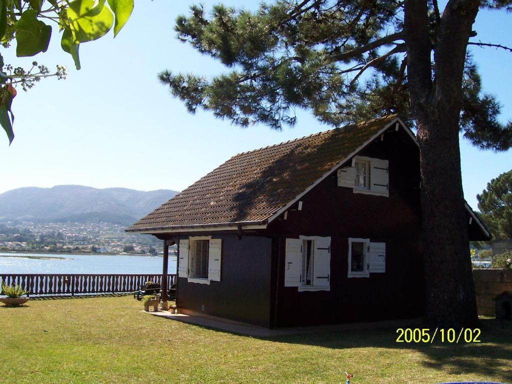 uma casa negra com uma árvore ao lado de um lago em Casa de Madera Sobre el Mar em Nigrán