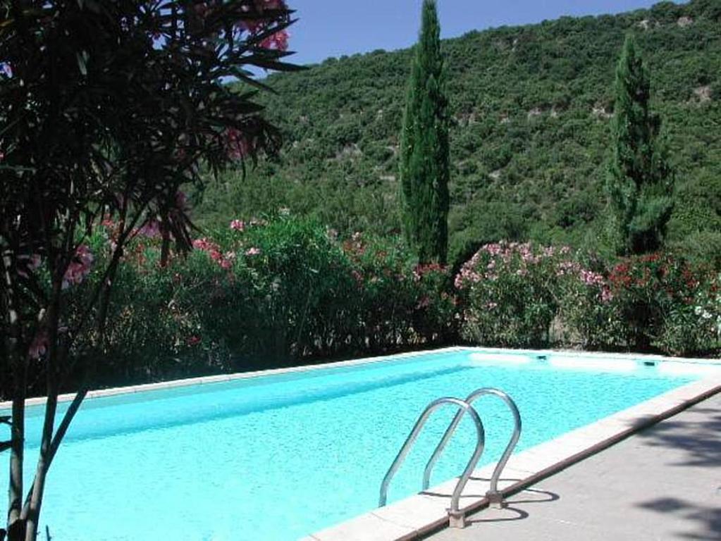 a blue swimming pool with two chairs in a garden at Chambres d'hôtes Domaine de Pélissols in Bédarieux