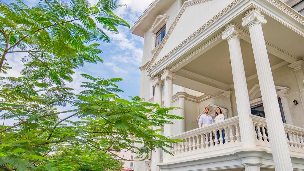 a bride and groom on the balcony of a white house at White Mansion 白色公馆 in Phnom Penh