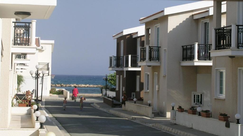 una mujer caminando por una calle al lado de algunos edificios en Philippou Beach Villas & Apartments, en Lárnaca