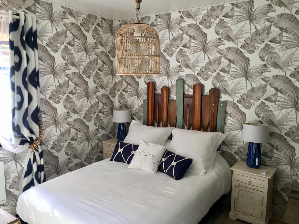 um quarto com uma cama branca e papel de parede tropical em Le Sitel em Le Brusc