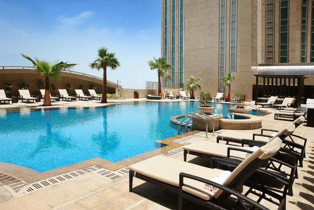 einen Pool mit Liegestühlen und ein Hotel in der Unterkunft Sofitel Abu Dhabi Corniche in Abu Dhabi