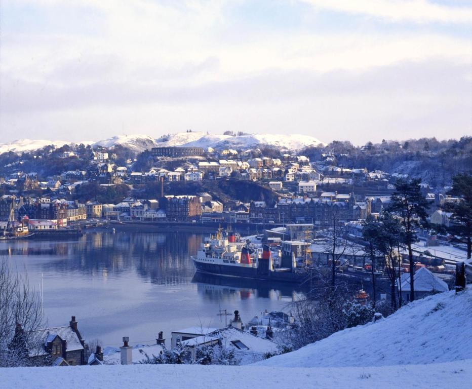 a river with a city and a boat in the water at Muthu Alexandra Hotel in Oban