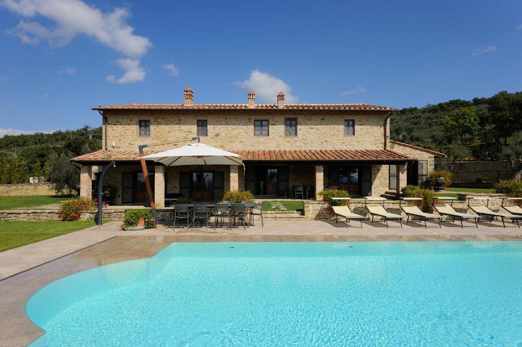 une maison avec une piscine en face d'un bâtiment dans l'établissement Villa Fontanicchio, à Tuoro sul Trasimeno