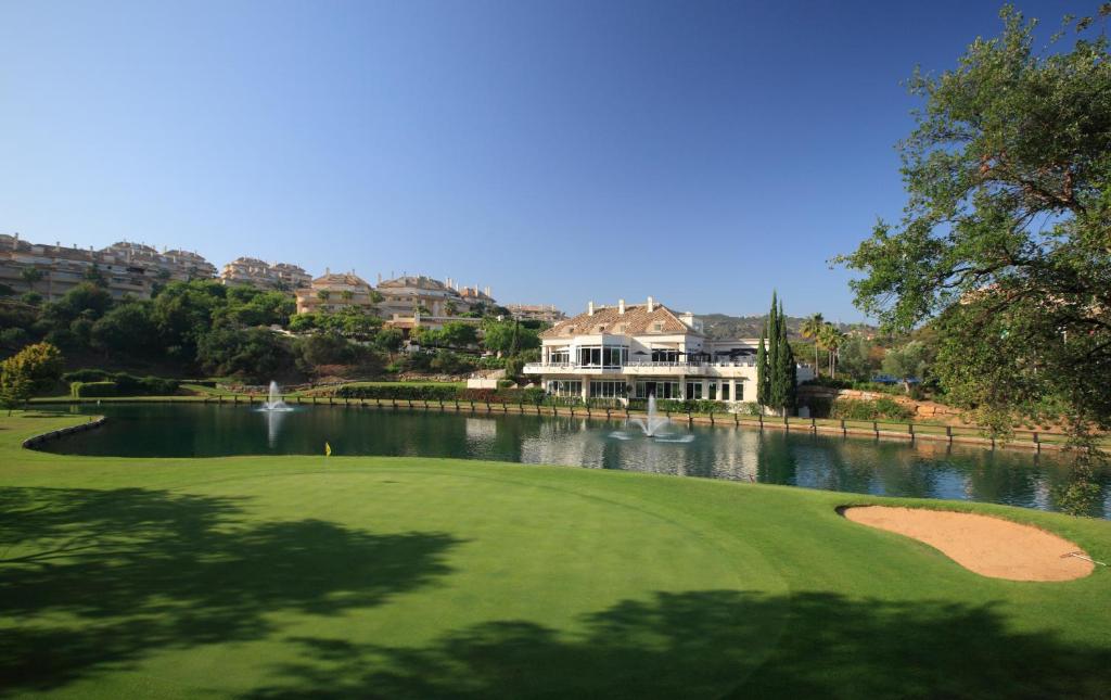 - un parcours de golf avec un lac et une maison dans l'établissement Hotel - Apartamentos Greenlife Golf, à Marbella