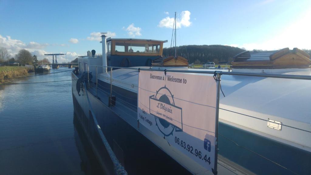 een grote boot is aangemeerd op het water bij l'Odyssée Péniche in Saint-Valery-sur-Somme