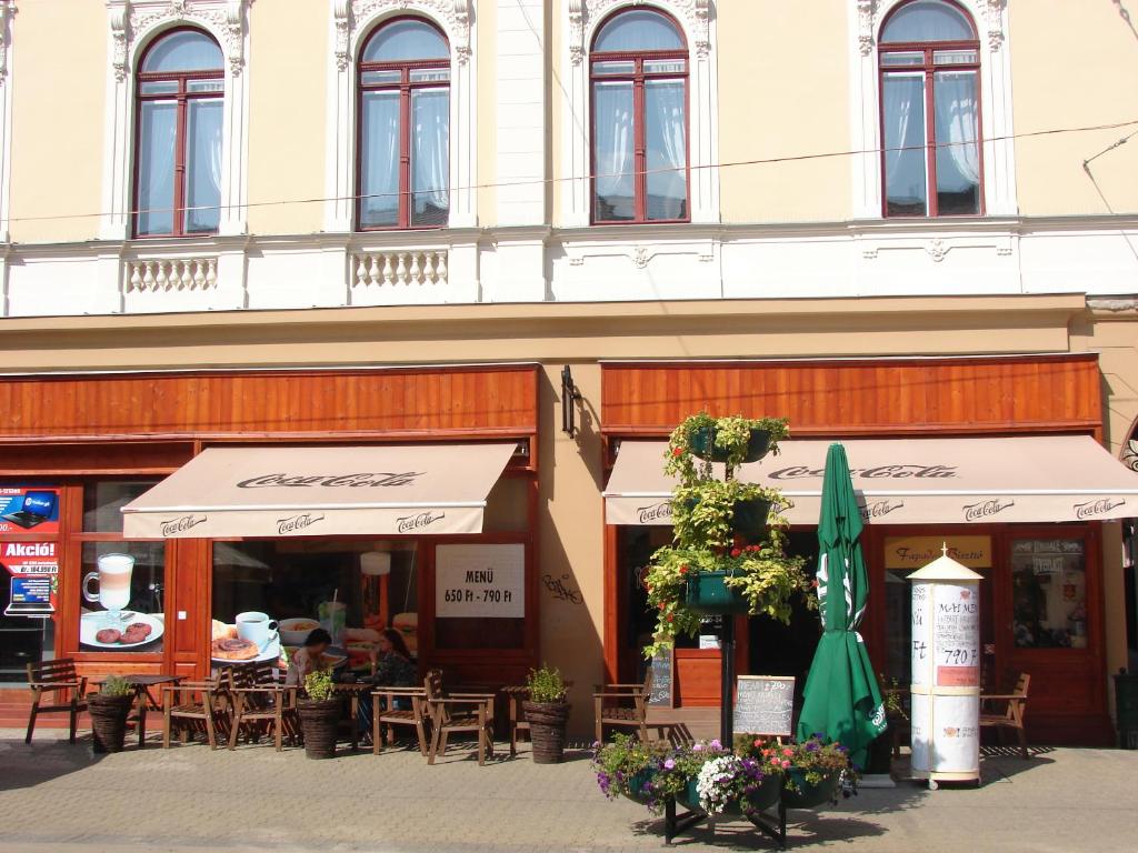 a restaurant with tables and umbrellas in front of a building at Promenade Panzió in Miskolc