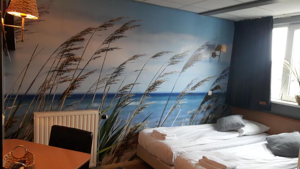 エイマイデンにあるホテル フェルセンの海と背の高い芝生の壁画が施されたベッドルーム