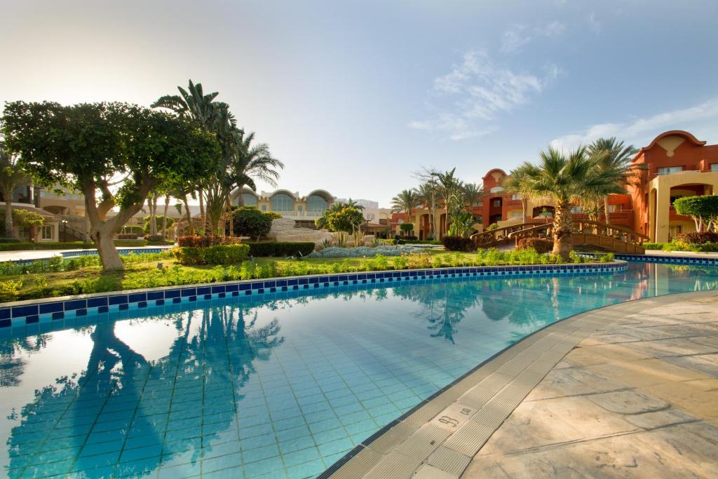 a swimming pool at a resort with palm trees and houses at Sharm Grand Plaza Resort - Families and Couples Only in Sharm El Sheikh