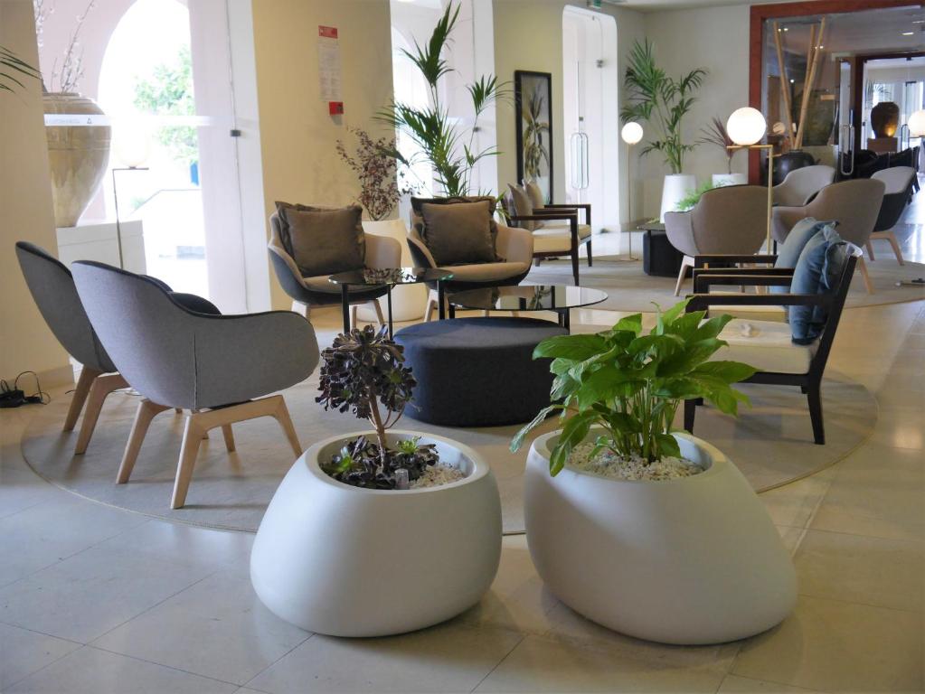 a lobby with chairs and potted plants on the floor at Azoris Faial Garden – Resort Hotel in Horta