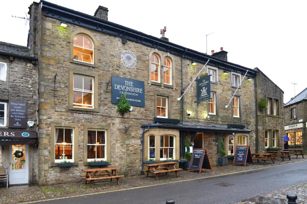 an old stone building with benches in front of it at The Devonshire Grassington in Grassington