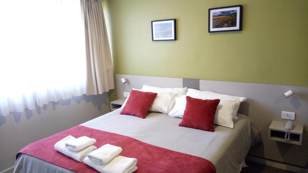 a bedroom with a large bed with red and white pillows at Estepa Hotel in General Roca