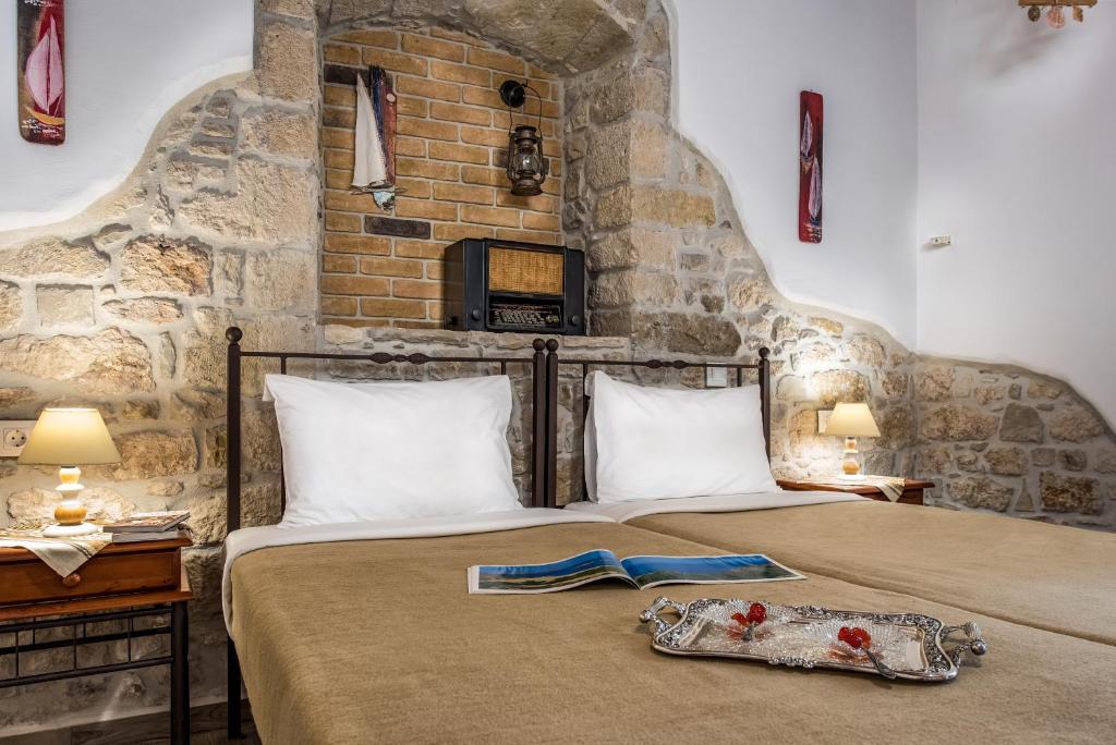 two beds in a room with a stone wall at Cretan Villa in Ierápetra