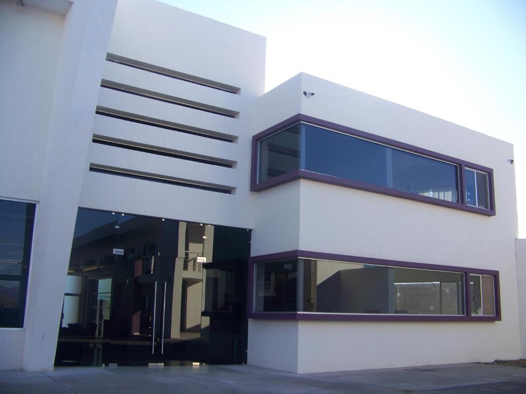 un edificio blanco con ventanas azules en un lateral en Hotel Oasis, en Heroica Caborca