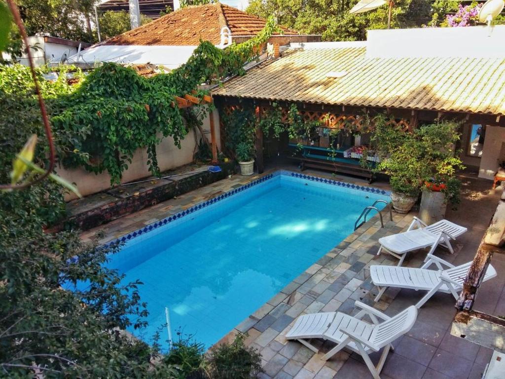 a swimming pool with two chairs and a house at Alpha Hospedaria & Hostel in Londrina