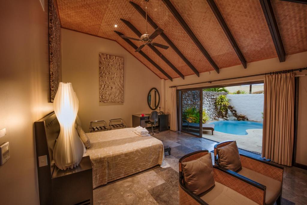 a bedroom with a bed and a pool at Crown Beach Resort & Spa in Rarotonga