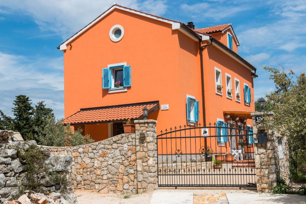 ein großes orangefarbenes Haus mit einem Steinzaun in der Unterkunft Apartmani Villa Casper in Veli Lošinj