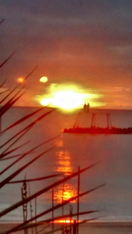 a sunset in the ocean with a boat in the water at Captains Lodge in Newbiggin-by-the-Sea