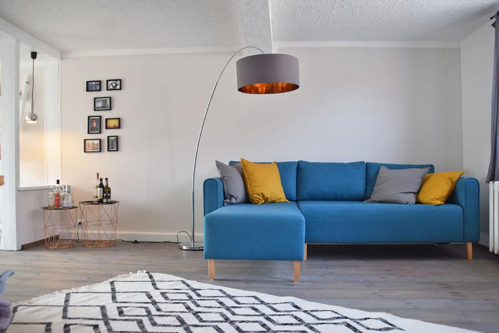 Sofá azul en la sala de estar con almohadas amarillas en Maison Cyriax, en Harzgerode