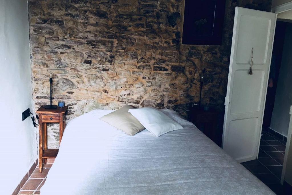 Cama en habitación con pared de piedra en El Baluard, en Cardona