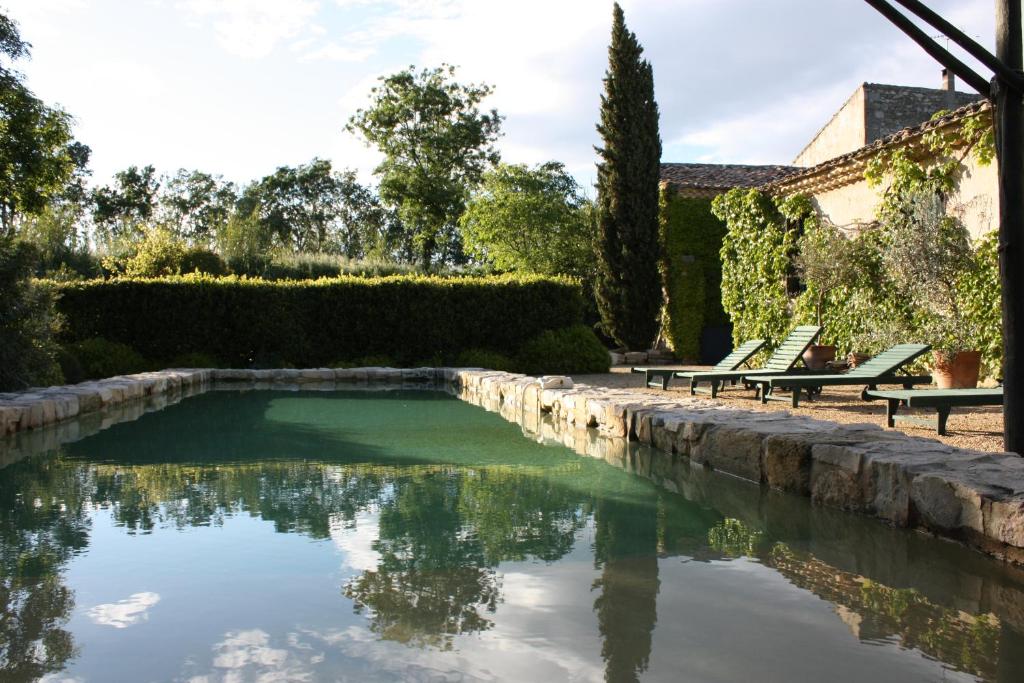 a swimming pool in a garden with two lawn chairs at Maison d'Hôtes Mas de Barbut in Saint-Laurent-dʼAigouze
