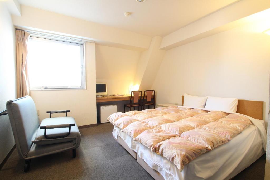 a bedroom with a bed and a desk and a window at Sakura Hotel Ikebukuro in Tokyo