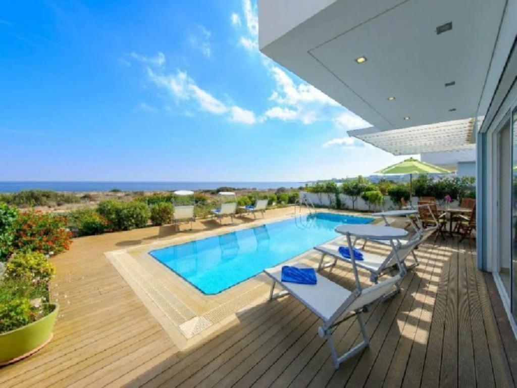 uma piscina num deque com mesa e cadeiras em “Your Luxury Sea Front Villa” – Protaras Villa 01 em Protaras