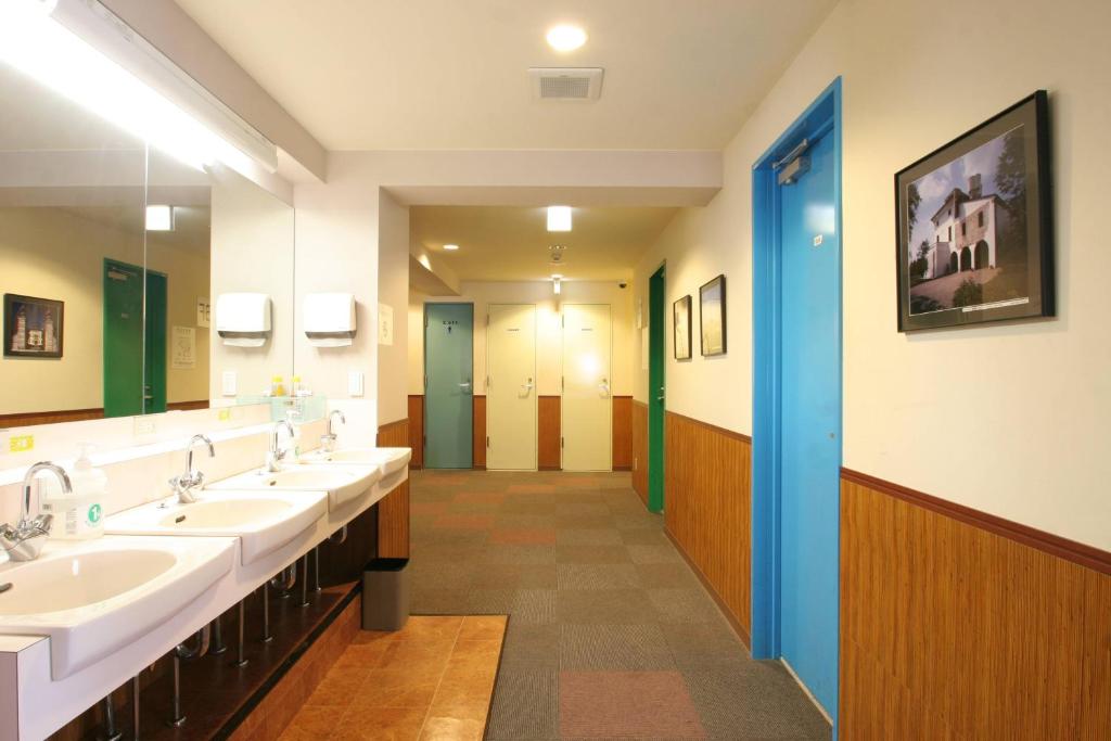a bathroom with three sinks and a row of mirrors at Sakura Hotel Ikebukuro in Tokyo