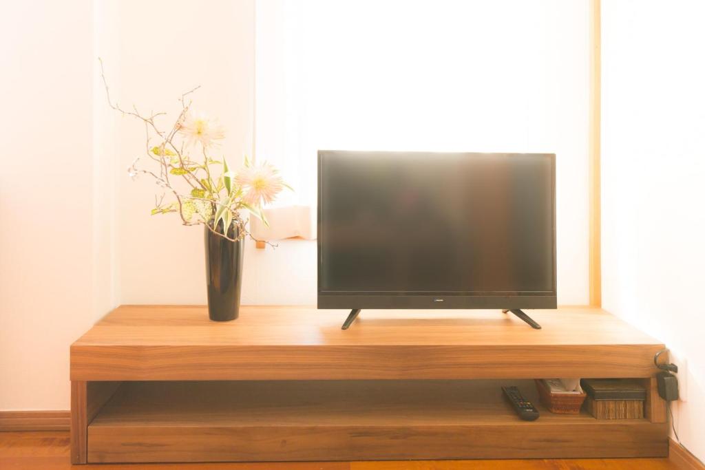 a television on a wooden stand with a vase of flowers at K&K Apartment Kita-Akabane #301 in Tokyo
