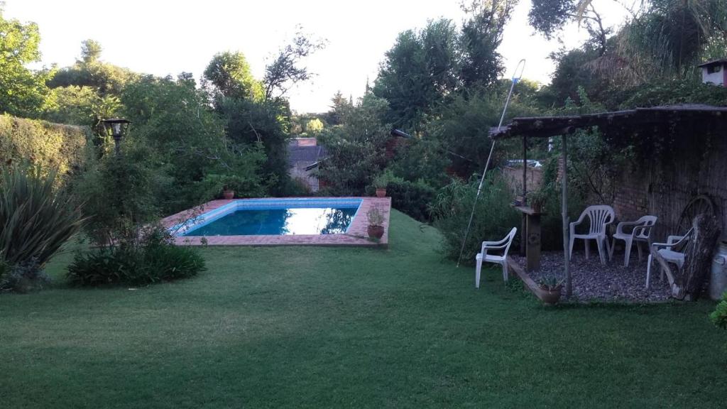 a backyard with a swimming pool and chairs in the grass at Cabaña El Cristo in La Cumbre