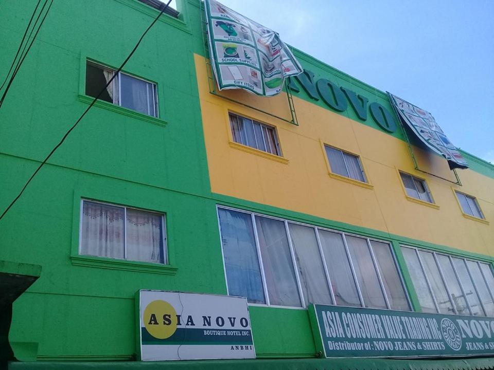 un bâtiment vert et jaune avec un panneau devant lui dans l'établissement Asia Novo Boutique Hotel - Roxas, à Roxas City