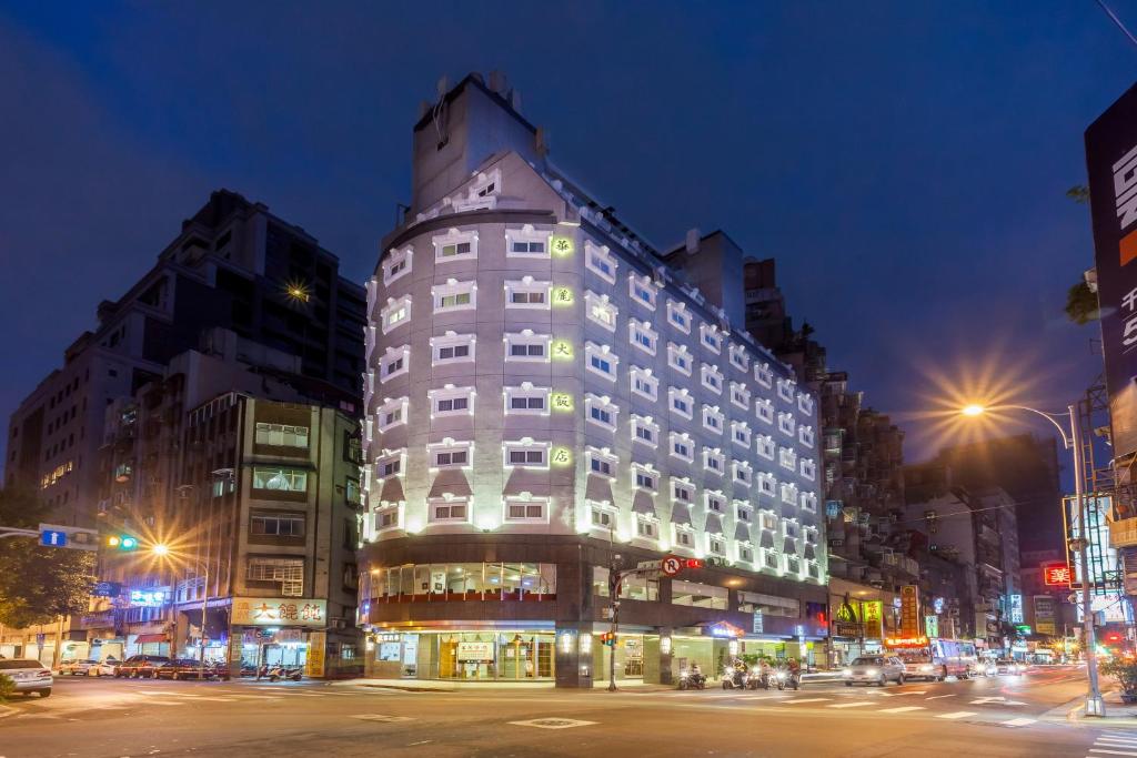 台北的住宿－華麗大飯店Ferrary Hotel，夜幕降临的城市街道上一座高大的白色建筑