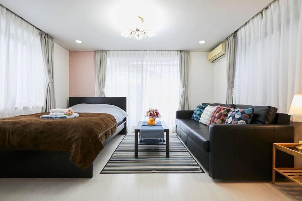 ein Schlafzimmer mit einem Bett und einem Sofa in der Unterkunft Luxury Guest House in Tokyo Shinjuku in Tokio