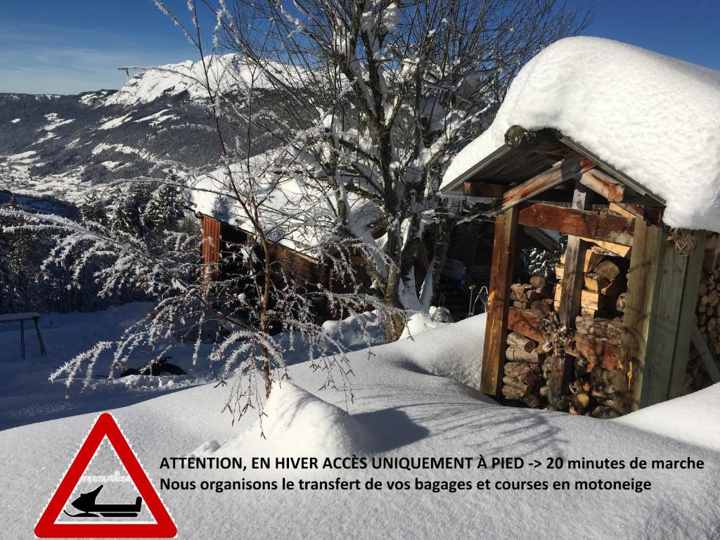 un bâtiment recouvert de neige avec un panneau d'avertissement dans l'établissement Les chalets du Rosay, à Saint-Jean-de-Sixt
