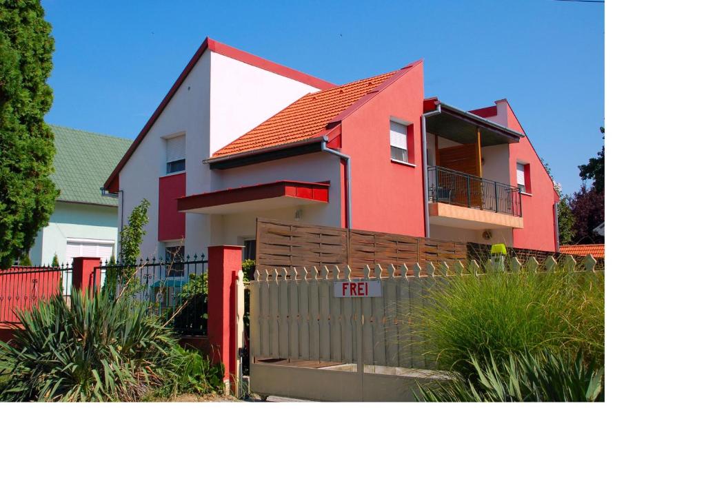 una casa roja y blanca con una valla en Laci Apartman, en Zalakaros